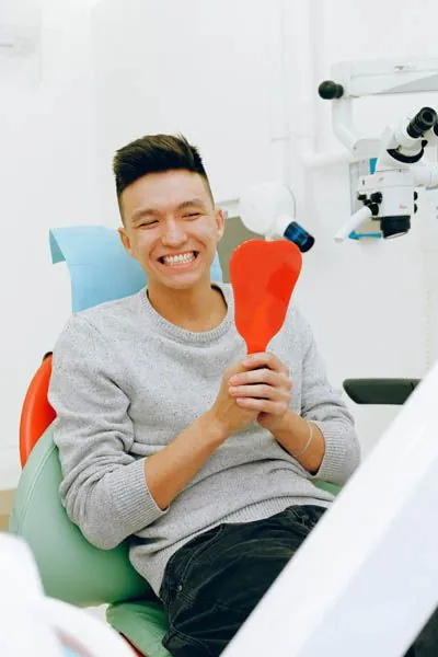 patient smiling big in the mirror after getting periodontal treatment at AZ Dental
